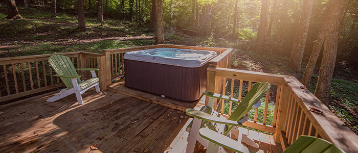 south seas spa in a woodland area, surrounded by deck rails and Adirondack chairs