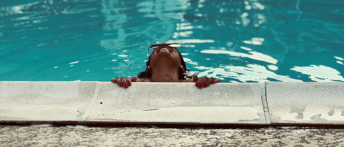 Woman in a pool holding on to the ledge and smiling